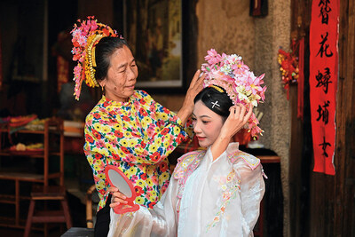 A tourist (right) is wearing flowery headwear at Xunpu Village of Quanzhou City, southeast China's Fujian Province, Aug. 27, 2025. (Provided by Zhou Yi)